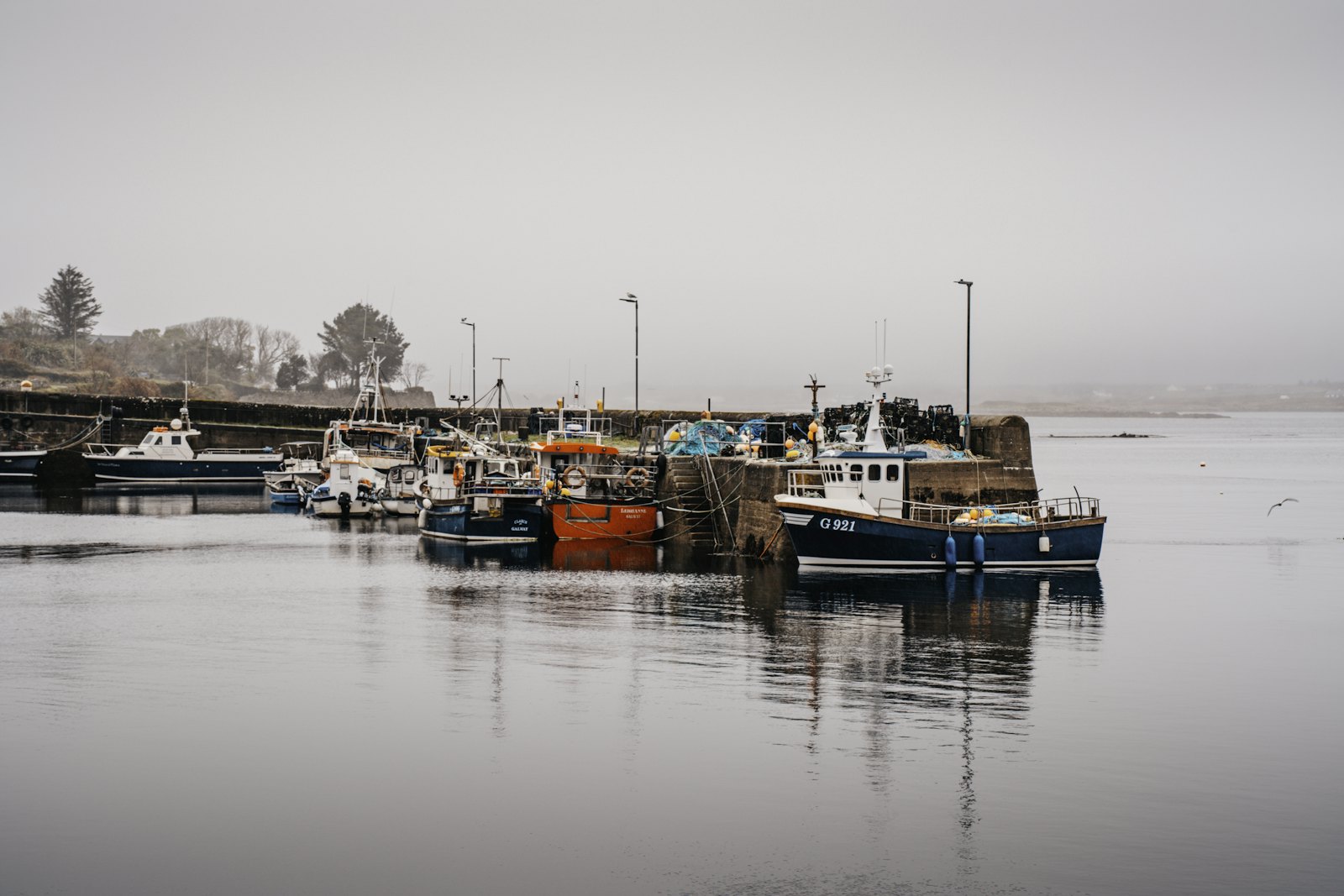 Fishing boats moored at a misty harbour wall on a still grey morning (placeholder photo)
