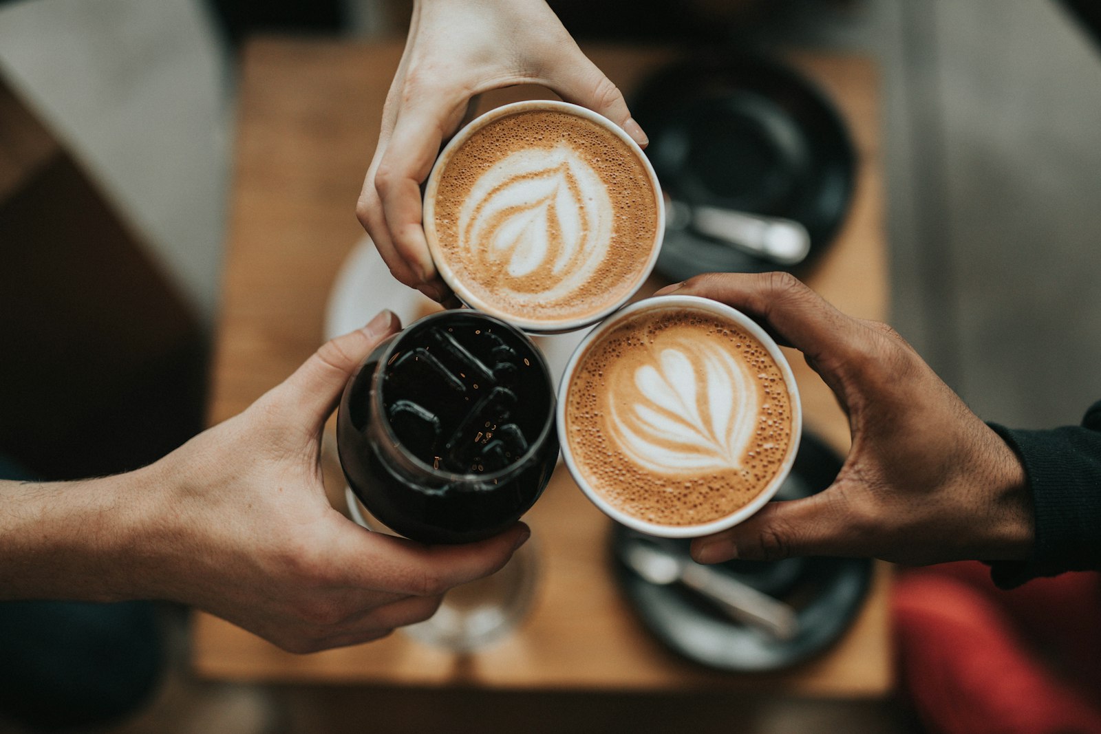 Three cups of coffee raised together over a wooden table (placeholder photo)